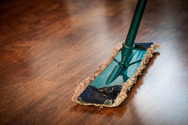 A mop cleaning a wooden floor during professional floor cleaning service.